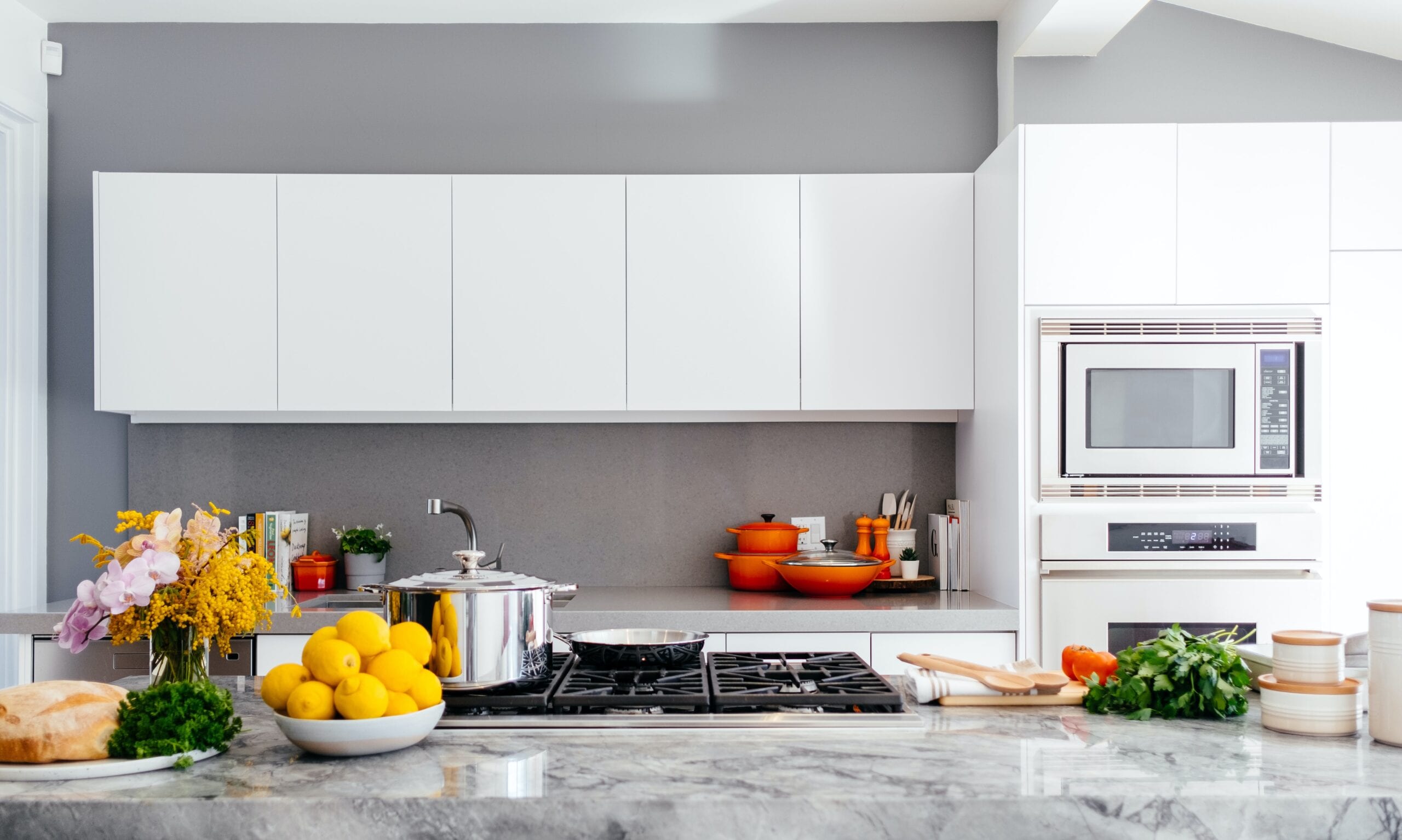 Kitchen with gray-white granite counters and white cabinets and gray walls.